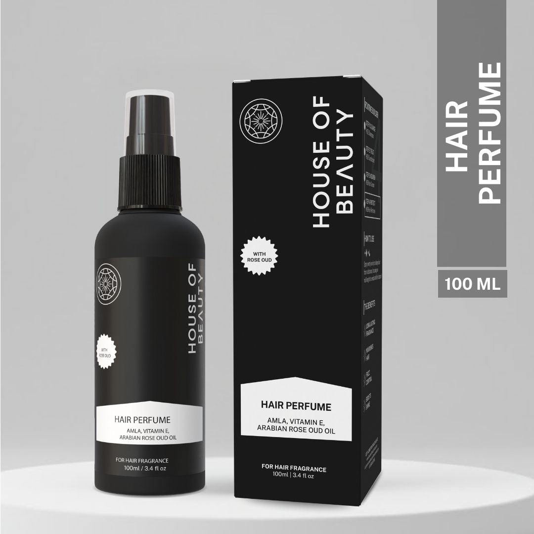 A sleek black bottle of House of Beauty Hair Perfume with packaging, featuring Amla, Vitamin E, and Arabian Rose Oud Oil. The bottle and box are displayed side by side on a minimalist, neutral background.