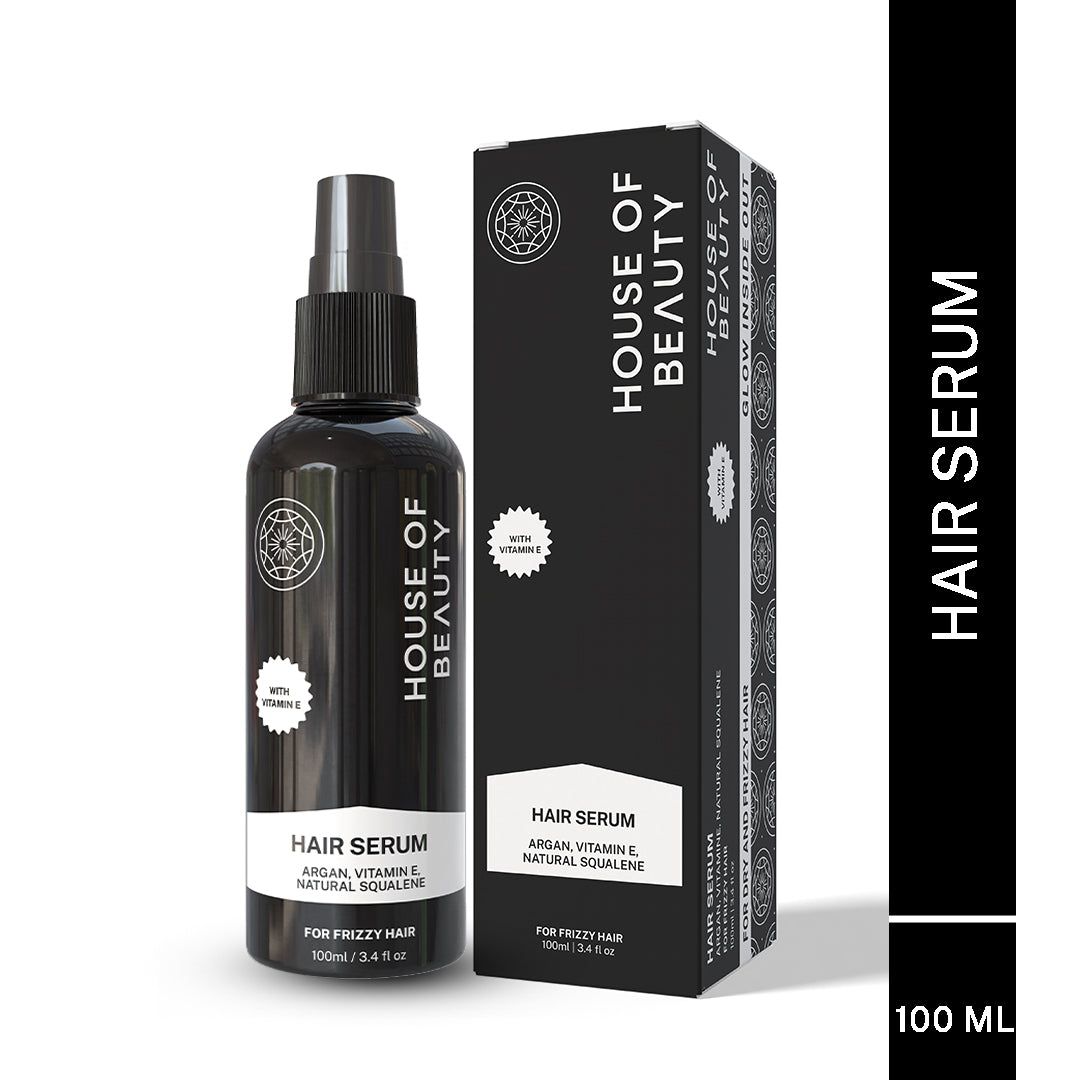 Product photo of the House of Beauty Hair Serum spray bottle and its box, labeled 100ml. Prominently features the ingredients: Argan, Vitamin E, and Natural Squalene, and states it is "For Frizzy Hair."