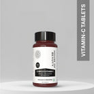 House of Beauty Complex Vitamin C tablets displayed on a minimal podium background with vertical “Vitamin-C Tablets” text banner.