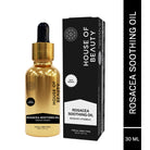 A professional studio shot featuring a gold 30ml metallic bottle of Rosacea Soothing Oil alongside its black and white retail box. The packaging emphasizes the presence of Rosehip and Vitamin E, suitable for all skin types.